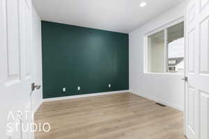 Empty room featuring light wood finished floors, baseboards, visible vents, and recessed lighting