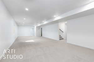 Finished basement featuring light carpet, stairs, baseboards, and recessed lighting