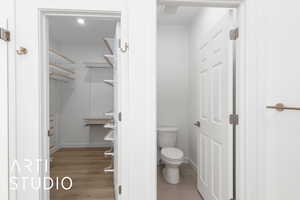 Bathroom featuring toilet, baseboards, and wood finished floors