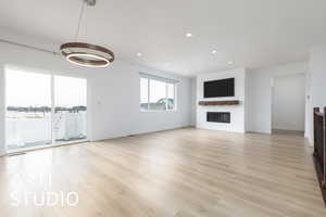 Unfurnished living room with a glass covered fireplace, light wood-style flooring, baseboards, and recessed lighting