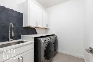 Washroom with washer and clothes dryer, light tile patterned floors, cabinet space, a sink, and baseboards