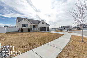 View of front of property featuring stucco siding, concrete driveway, a front lawn, and fence