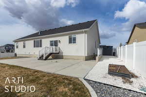 Rear view of house with a vegetable garden, a fenced backyard, a patio, and stucco siding