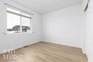 Spare room featuring light wood-type flooring, baseboards, and visible vents