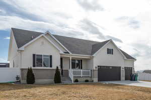 View of front of property with brick siding, covered porch, an attached garage, fence, and driveway