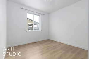 Empty room featuring light wood-style floors, visible vents, and baseboards