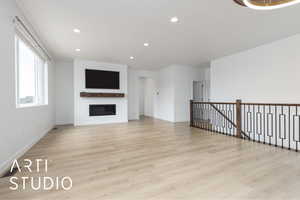 Unfurnished living room with baseboards, a glass covered fireplace, light wood-style flooring, and recessed lighting