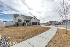 View of front of home with concrete driveway, a front yard, fence, and stucco siding