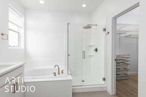 Bathroom featuring a stall shower, recessed lighting, a garden tub, and vanity