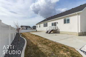 Rear view of house featuring stucco siding, a fenced backyard, roof with shingles, and a patio