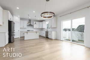 Kitchen with a center island, light countertops, appliances with stainless steel finishes, a sink, and wall chimney exhaust hood