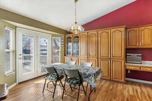 Dining area featuring light wood finished floors, baseboards, and vaulted ceiling