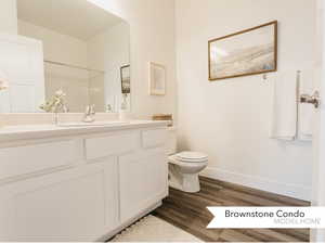 Bathroom with baseboards, vanity, toilet, and wood finished floors