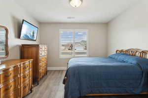 Bedroom featuring light wood finished floors, visible vents, and baseboards