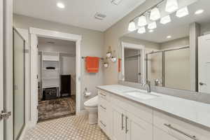 Bathroom featuring toilet, vanity, visible vents, a shower stall, and a walk in closet