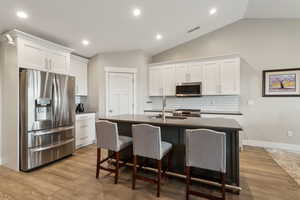 Kitchen with stainless steel appliances, a sink, visible vents, white cabinets, and dark countertops