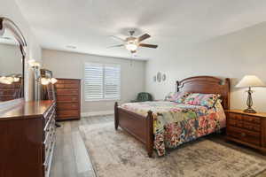 Bedroom featuring baseboards, a textured ceiling, a ceiling fan, and wood finished floors