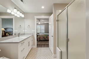 Full bathroom featuring visible vents, ensuite bathroom, a stall shower, ceiling fan, and vanity