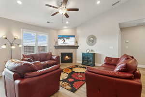 Living area with ceiling fan, visible vents, vaulted ceiling, and wood finished floors