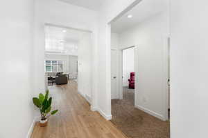 Hallway with baseboards, visible vents, and light wood finished floors