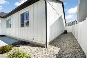 View of side of home featuring board and batten siding, a fenced backyard, and cooling unit
