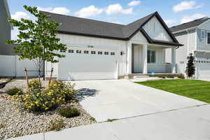 Modern farmhouse featuring a garage, fence, driveway, roof with shingles, and board and batten siding