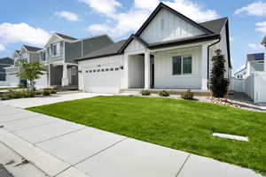 View of front of house featuring concrete driveway, an attached garage, fence, a front lawn, and board and batten siding