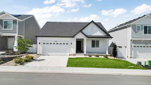View of front of house with driveway, a shingled roof, an attached garage, fence, and board and batten siding