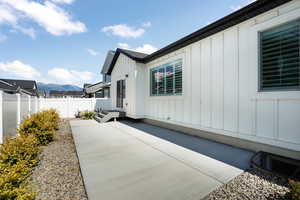 View of side of property with fence, a mountain view, board and batten siding, and a patio
