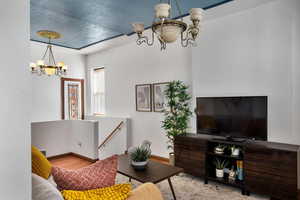 Living area with baseboards, wood finished floors, and a notable chandelier