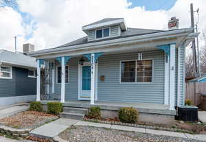 Bungalow with a porch, central AC, a chimney, and roof with shingles