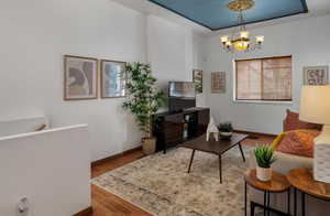 Living area with baseboards, wood finished floors, and an inviting chandelier