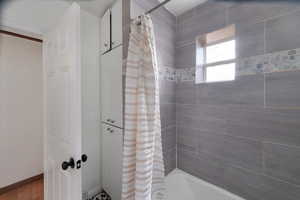 Bathroom featuring baseboards and shower / tub combo with curtain