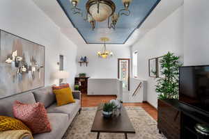 Living room with an inviting chandelier, a tray ceiling, and wood finished floors