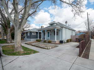 View of front of home with a porch, fence, a chimney, and central air condition unit