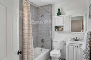 Bathroom featuring toilet, shower / bath combo with shower curtain, and vanity