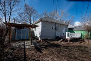 Back of house with a storage shed, an outbuilding, and a wooden deck