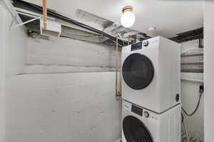 Washroom with stacked washer and dryer and laundry area