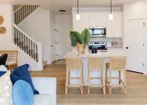 Kitchen with appliances with stainless steel finishes, light countertops, decorative light fixtures, and a kitchen island with sink