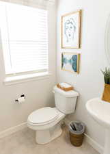 Half bath with baseboards, a sink, toilet, and tile patterned floors