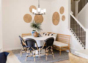 Dining room featuring a notable chandelier, wood finished floors, visible vents, baseboards, and stairs