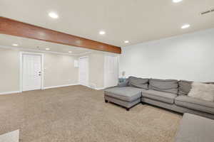 Carpeted living room featuring baseboards, ornamental molding, and a textured ceiling