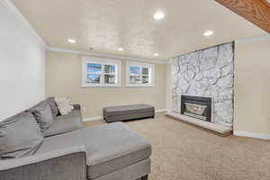 Living area with crown molding, a fireplace, carpet flooring, a textured ceiling, and baseboards