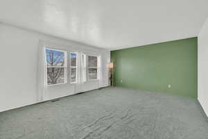 Spare room with carpet, visible vents, and a textured ceiling