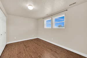 Bedroom featuring a textured ceiling, dark wood-style flooring, visible vents, and baseboards