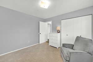 Bedroom room with light carpet, a textured ceiling, and baseboards