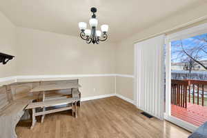 Dining area with an inviting chandelier, plenty of natural light, visible vents, and wood finished floors