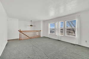 Spare room with a ceiling fan, a textured ceiling, visible vents, and carpet flooring