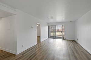 Unfurnished room featuring a textured ceiling, baseboards, and wood finished floors