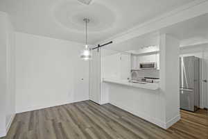 Kitchen with stainless steel appliances, a barn door, dark wood-style flooring, and a sink